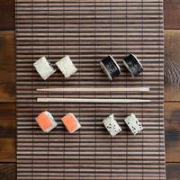 Sushi rolls and wooden chopsticks lie on a bamboo straw serwing mat. Traditional Asian food. Top view photo