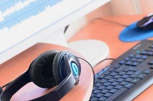 Big black headphones lie on the wooden desktop of the sound designer photo