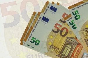 Los billetes de 50 euros se encuentran apilados sobre el fondo de un gran billete semitransparente. presentación abstracta de la moneda nacional foto