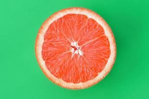 Top view of an one grapefruit slice on bright background in green color. A saturated citrus texture image photo