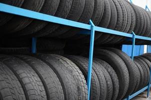 Rack with variety of car tires in automobile store. Many black tires. Tire stack background photo