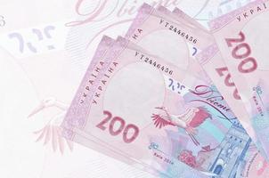 200 billetes de hryvnias ucranianos se encuentran apilados en el fondo de un gran billete semitransparente. presentación abstracta de la moneda nacional foto