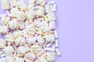 Colorful marshmallow laid out on violet paper background. pastel creative texture. minimal photo