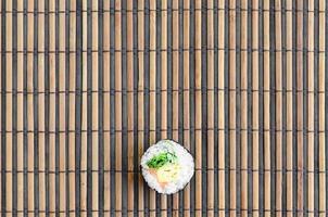 Sushi roll lie on a bamboo straw serwing mat. Traditional Asian food. Top view. Flat lay minimalism shot with copy space photo