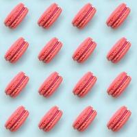 Pink dessert cake macaron or macaroon on trendy pastel blue background top view. Flat lay pattern composition photo