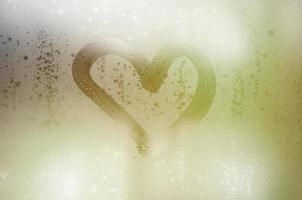 The heart is painted on the misted glass in winter photo