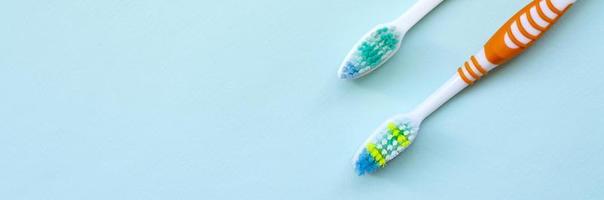 Two toothbrushes lie on a pastel blue background. Top view, flat lay. Minimal concept photo