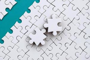 The blue path is laid on the platform of a white folded jigsaw puzzle. The missing elements of the puzzle are stacked nearby. Texture image with space for text photo
