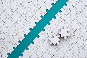 The blue path is laid on the platform of a white folded jigsaw puzzle. The missing elements of the puzzle are stacked nearby. Texture image with space for text photo