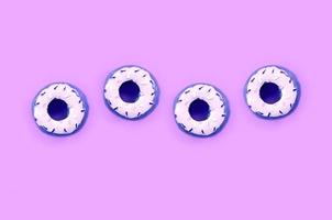 Many small plastic donuts lies on a pastel colorful background. Flat lay minimal pattern. Top view photo