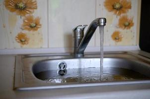 Stainless steel sink plug hole close up full of water and particles of food photo