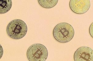 Many golden bitcoins lies on a blanket made of soft and fluffy light orange fleece fabric. Physical visualization of virtual crypto currency photo