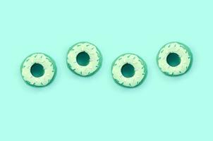 Many small plastic donuts lies on a pastel colorful background. Flat lay minimal pattern. Top view photo