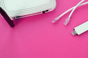 Internet router, portable USB wi-fi adapter and internet cable plugs lie on a bright pink background. Items required for internet photo