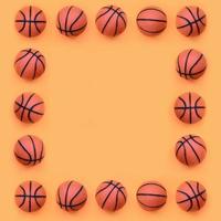 el marco de muchas bolas naranjas pequeñas para el juego deportivo de baloncesto se encuentra en el fondo de textura del papel de color naranja pastel de moda en un concepto mínimo foto