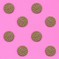 Pattern of a brown biscuits on a pink background. Trendy minimal concept of food and dessert. Abstract flat lay, top view photo