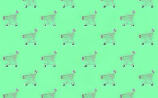 Shopping addiction, shopping lover or shopaholic concept. Many small empty shopping carts perform a pattern on a pastel colored paper background. Flat lay composition, top view photo