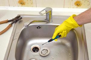 Close-up of handsome plumber hands repairing drain of kitchen sink photo