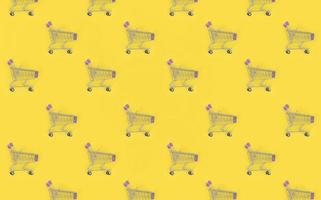 Shopping addiction, shopping lover or shopaholic concept. Many small empty shopping carts perform a pattern on a pastel colored paper background. Flat lay composition, top view photo