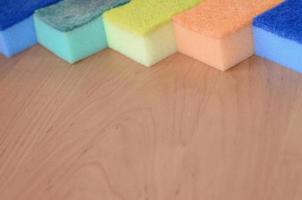 A few kitchen sponges lie on a wooden kitchen countertop. Colorful objects for washing dishes and cleaning in the house are ready for use photo