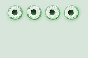 Many small plastic donuts lies on a pastel colorful background. Flat lay minimal pattern. Top view photo