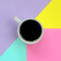 Small white coffee cup on texture background of fashion pastel blue, yellow, violet and pink colors paper in minimal concept photo