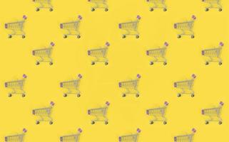 Shopping addiction, shopping lover or shopaholic concept. Many small empty shopping carts perform a pattern on a pastel colored paper background. Flat lay composition, top view photo