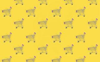 Shopping addiction, shopping lover or shopaholic concept. Many small empty shopping carts perform a pattern on a pastel colored paper background. Flat lay composition, top view photo