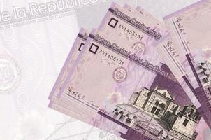 Los billetes de 50 pesos dominicanos se encuentran apilados sobre el fondo de un gran billete semitransparente. presentación abstracta de la moneda nacional foto