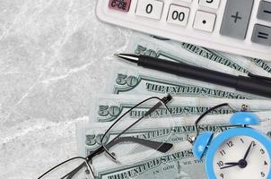 50 US dollars bills and calculator with glasses and pen. Business loan or tax payment season concept. Time to pay taxes photo