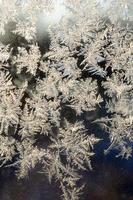 Snowflakes frost rime macro on window glass pane photo