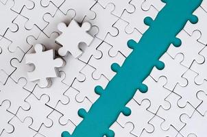The blue path is laid on the platform of a white folded jigsaw puzzle. The missing elements of the puzzle are stacked nearby. Texture image with space for text photo