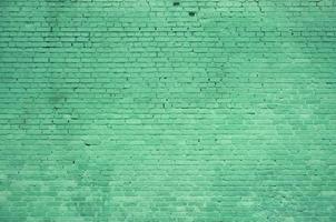 The texture of the brick wall of many rows of bricks painted in green color photo