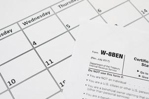IRS Form W-8BEN Certificate of foreign status of beneficial owner for United States tax withholding and reporting for individuals blank lies on empty calendar page photo