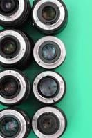 Several photographic lenses lie on a bright turquoise background. Copy space photo