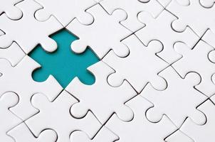 Close-up texture of a white jigsaw puzzle in assembled state with missing elements forming a blue pad for text. Copy space photo