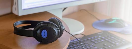 Big black headphones lie on the wooden desktop of the sound designer photo