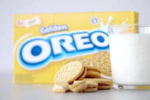 ternopil, ucrania - 28 de mayo de 2022 galletas oreo doradas crujientes con un vaso de leche sobre fondo blanco. la marca oreo es propiedad de la empresa mondelez international foto