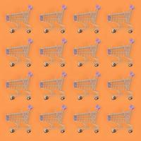 Shopping addiction, shopping lover or shopaholic concept. Many small empty shopping carts perform a pattern on a pastel colored paper background. Flat lay composition, top view photo