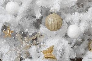 Decorating Christmas tree close up. Decoration bulb, white fir tree, golden x-mas toys and lights. Use for Christmas and New years celebration background photo