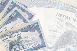 50 Nepalese rupees bills lies in stack on background of big semi-transparent banknote. Abstract business background photo