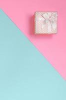 Small pink gift box lie on texture background of fashion pastel blue and pink colors paper in minimal concept photo