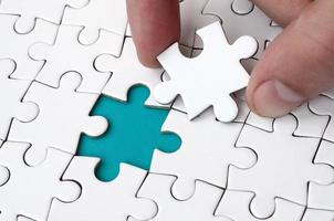 The human hand fills the last missing elements of the surface from the jigsaw puzzle. The concept of the completion of the initiated cases photo