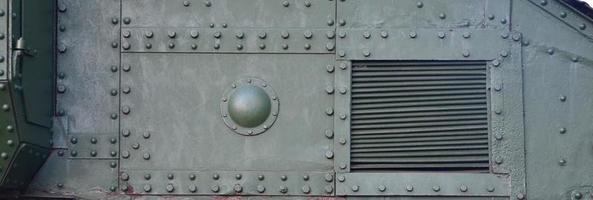 Texture of tank side wall, made of metal and reinforced with a multitude of bolts and rivets photo