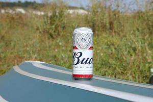 SUMY, UKRAINE - AUGUST 01, 2022 Can of Budweiser Lager Alcohol Beer on overturned kayak boat outdoors. Budweiser is a Brand from Anheuser-Busch Inbev photo