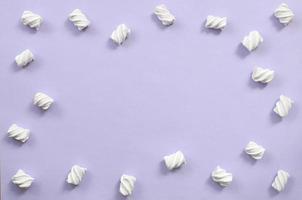 Colorful marshmallow laid out on violet paper background. pastel creative textured framework. minimal photo