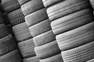 Old used tires stacked with high piles in secondary car parts shop garage photo