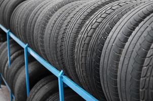 Rack with variety of car tires in automobile store. Many black tires. Tire stack background photo