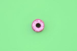 Single small plastic donut lies on a pastel colorful background. Flat lay minimal composition. Top view. photo