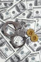 las esposas de la policía y los bitcoins se encuentran en una gran cantidad de billetes de un dólar. el concepto de problemas con la ley durante la minería ilegal de criptomonedas y las operaciones de bitcoin foto